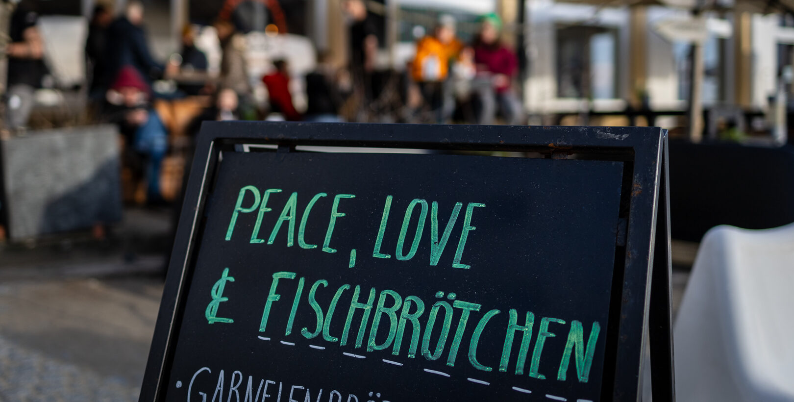 Auf einem schwarzen Aussteller in grüner Kreide Schrift steht'